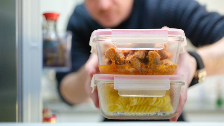 A person storing food in containers in the fridge.