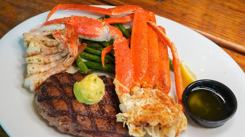 Seasoned crab and shrimp next to a steak topped with butter